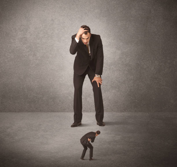 istock Big business man looking at small worker 1184582839