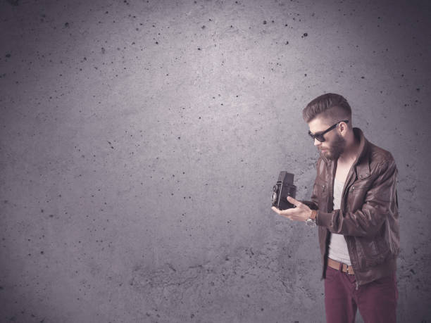 One man, modern redhead gentleman standing on the city street downtown, he is holding a camera and taking pictures.