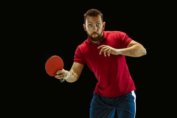 istock Young man playing table tennis on black studio background 1184585439