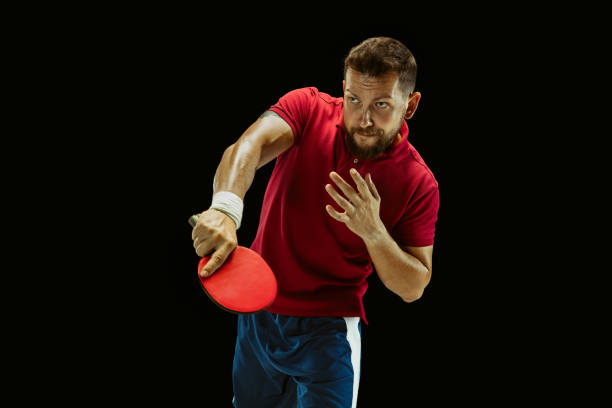 istock Young man playing table tennis on black studio background 1184585448