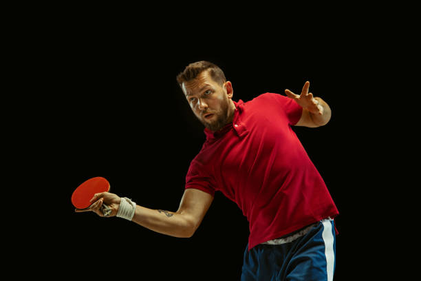 istock Young man playing table tennis on black studio background 1184585461