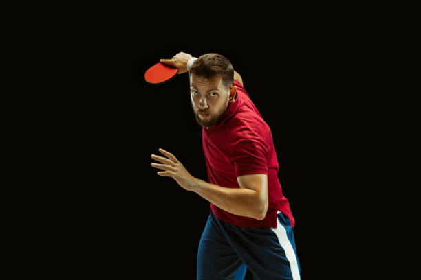 istock Young man playing table tennis on black studio background 1184585474