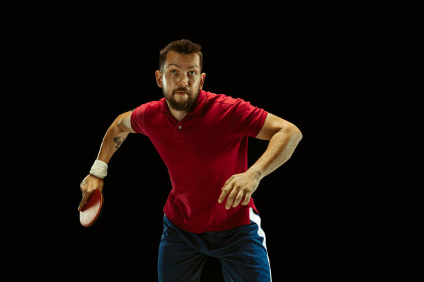 istock Young man playing table tennis on black studio background 1184585475