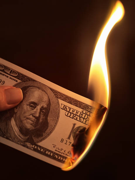 istock Hand holds burning US 100 dollar banknote 1184585886