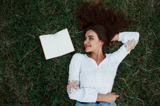 istock Notepad on the side. Girl lying down on the green grass and have a rest 1184589077