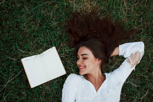 istock Top view. Girl lying down on the green grass and have a rest 1184589096