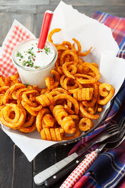 Basket full of curly fries Basket full of crunchy curly fries with a jar of dip curly fries stock pictures, royalty-free photos & images
