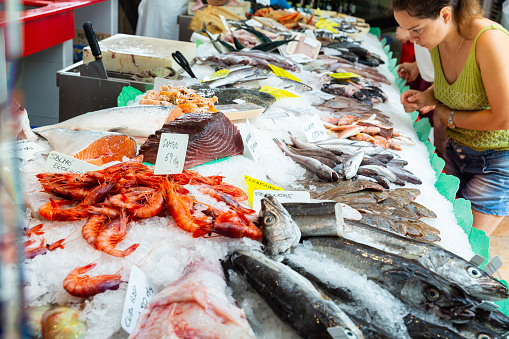 View of large assortment of fresh seafoods on icy showcase of fish store
