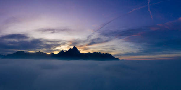 sul tappeto nuvola con montagne hahnenkamm al tramonto nebbioso a reutte - hahnenkamm foto e immagini stock