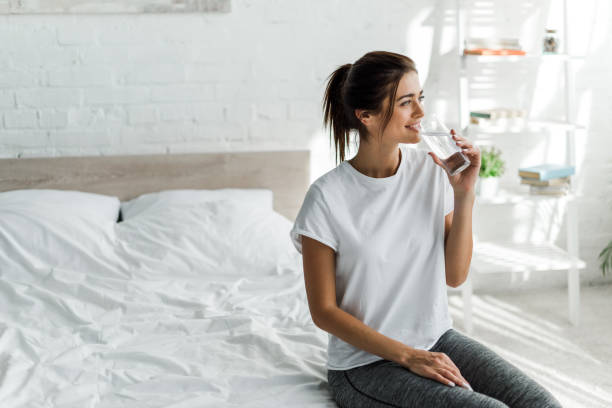 belle fille heureuse retenant l'eau potable du verre le matin - house home interior water glass photos et images de collection