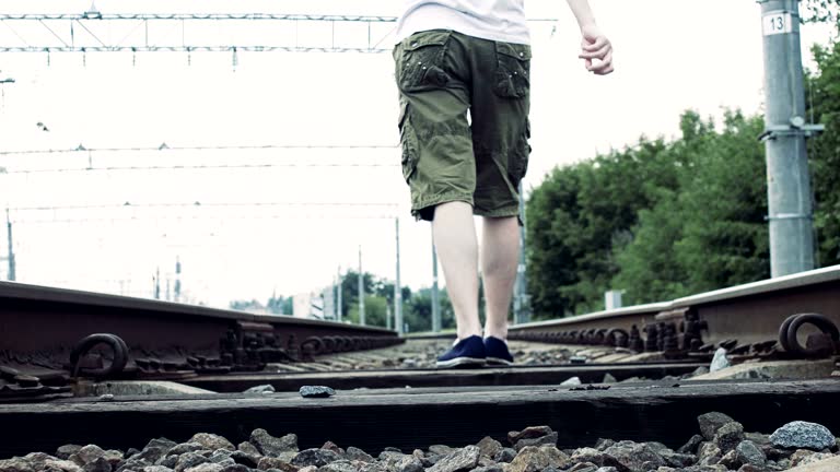 man with headphones walks along the railway, dangerous for life