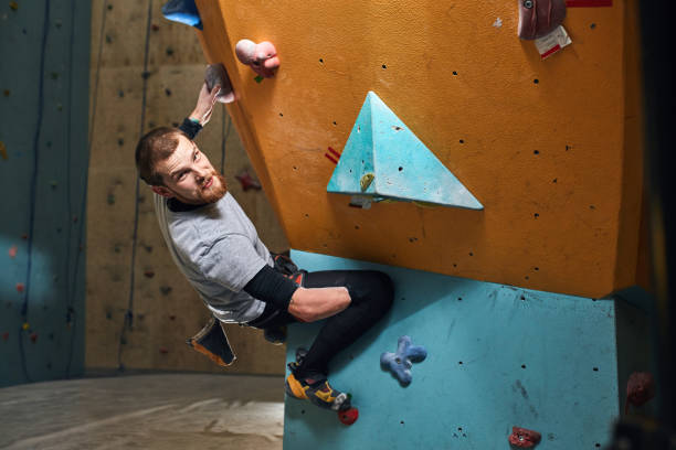 istock Young physically challenged boulderer hanging at colourful climbing wall 1184596163