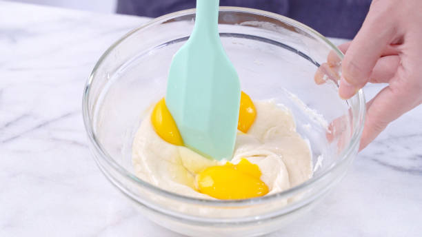 istock Mixing egg yolk into cake batter with green rubber spatula mixer tool stirring until smooth and blend well in a glass bowl. 1184602238