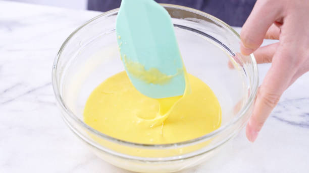 istock Mixing egg yolk into cake batter with green rubber spatula mixer tool stirring until smooth and blend well in a glass bowl. 1184602239