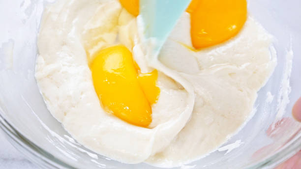 istock Mixing egg yolk into cake batter with green rubber spatula mixer tool stirring until smooth and blend well in a glass bowl. 1184602257