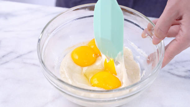 istock Mixing egg yolk into cake batter with green rubber spatula mixer tool stirring until smooth and blend well in a glass bowl. 1184602278