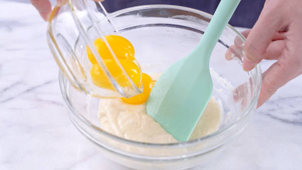 istock Mixing egg yolk into cake batter with green rubber spatula mixer tool stirring until smooth and blend well in a glass bowl. 1184602307