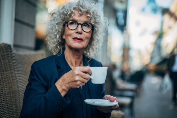 istock Mature lady drinking coffee in cafe outdoors 1184602924
