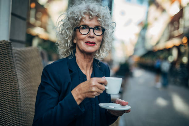 dojrzała kobieta pijąca kawę w kawiarni na świeżym powietrzu - sidewalk cafe cafe stockholm sweden zdjęcia i obrazy z banku zdjęć
