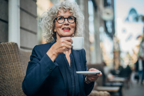 istock Mature lady drinking coffee in sidewalk cafe 1184603536