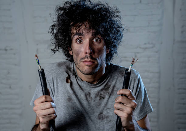 istock Funny man with burns and smoke holding electrical cable after getting a electric shock at home. Sad husband with dirty burnt face guilty expression. Domestic accidents, DYI and Electricity danger. 1184605133