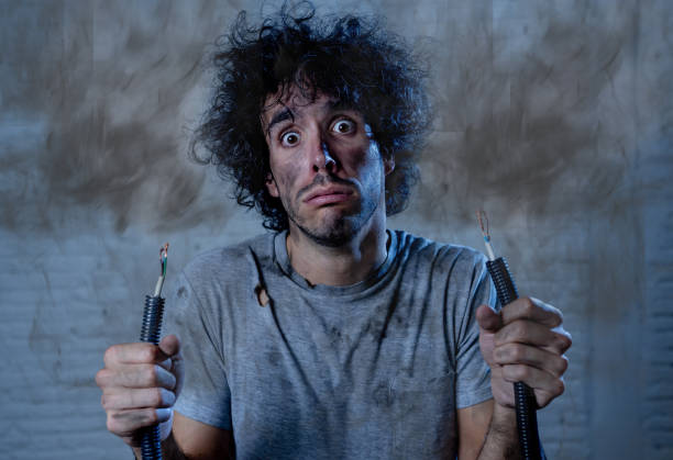 istock Funny man with burns and smoke holding electrical cable after getting a electric shock at home. Sad husband with dirty burnt face guilty expression. Domestic accidents, DYI and Electricity danger. 1184605272