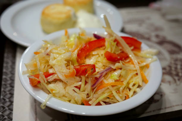 Fresh healthy vegetable salad with cabbage which mixed with red sweet pepper in a white plate. Concept of healthy vegetarian food. Selective focus. Close-up.