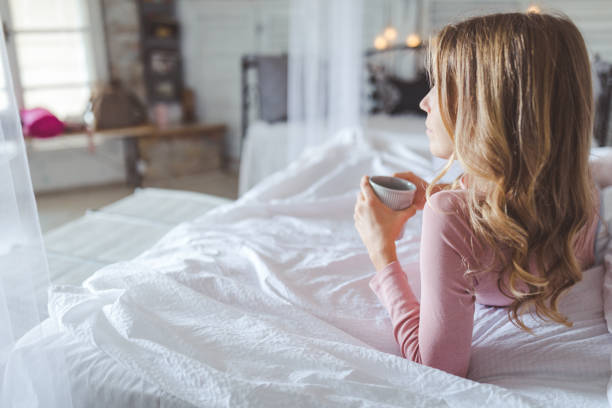istock Beautiful young woman drinking coffee at home 1184606772