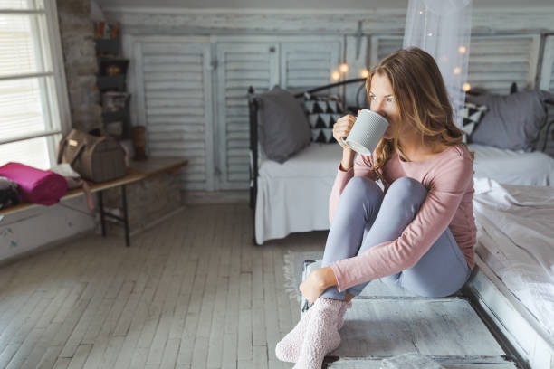 schöne junge frau trinkt kaffee zu hause - indoors window elegance tranquil scene stock-fotos und bilder