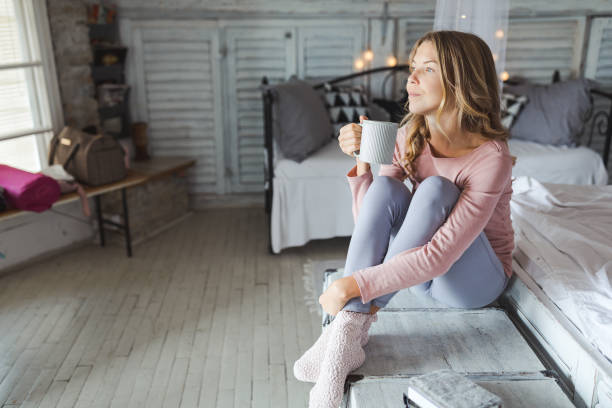 istock Beautiful young woman drinking coffee at home 1184607453