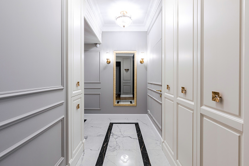Entrance hallway in a modern apartment with a luxurious design: grey walls, built-in wardrobe, classic style
