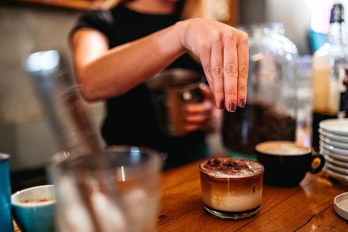 Young female barista making Coffee For Customers At Cafe. Latte art.