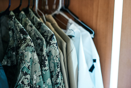 Shot of various military jackets hanging in a closet