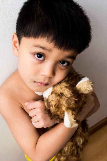 istock boy hugged his doll and had a sad and worried look and expression. 1184613005