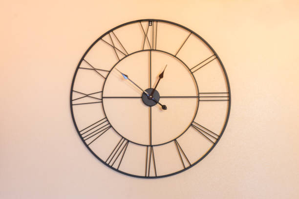 istock metal wire clock hanging on orange wall 1184615035