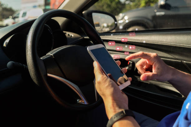 istock Man looking at mobile phone while driving a car.Dangerous driver ,or  Young male driver using touch screen smartphone and gps navigation in a car. 1184621801