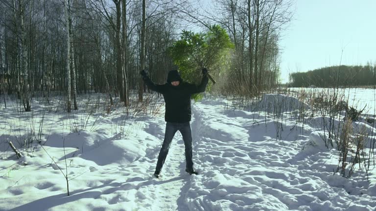 Funny man dancing with christmas tree in hand in the winter in the forest before new year in the town. Concept begin of celebration. Slow motion