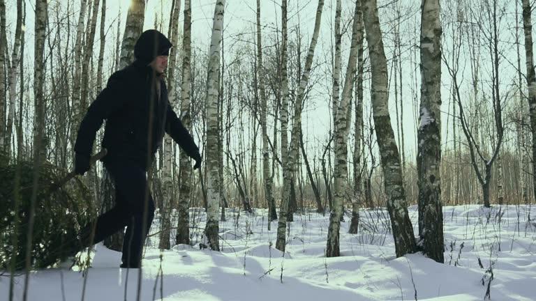 Man drags a felled christmas tree in the snow to his home and walk in the forest in the snow before new year in the town. Concept begin of celebration. Slow motion