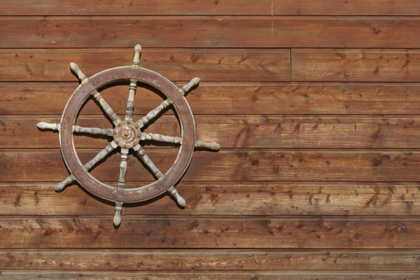 istock Old ship steering wheel hangs on the wooden wall 1184627262