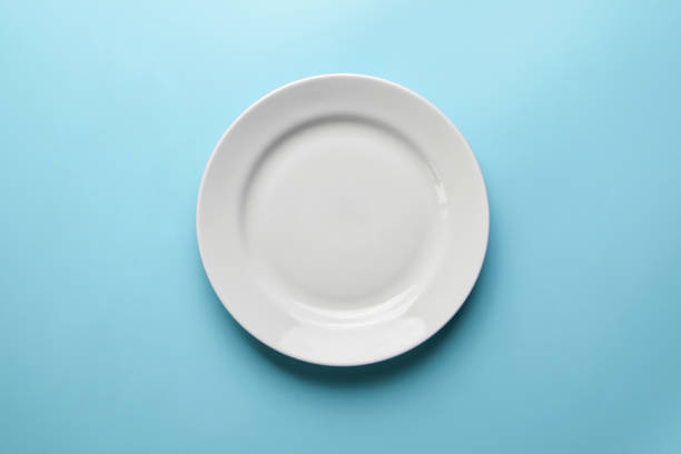 istock Empty plate on blue background, copy space. Restaurant business went broke concept. Visitor of an luxury restaurant is waiting for an order. 1184627704