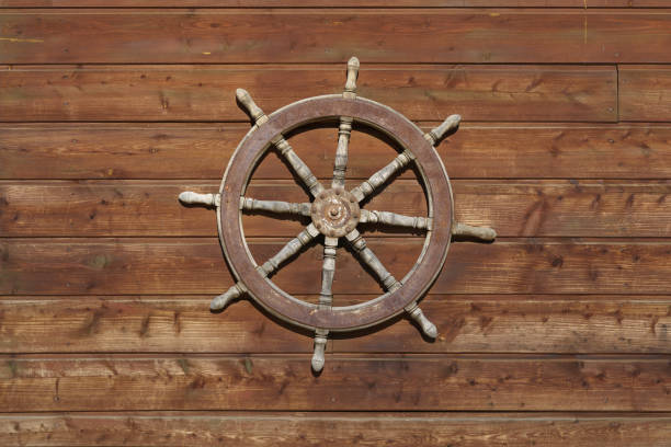 istock Old ship steering wheel hangs on the wooden wall 1184628378