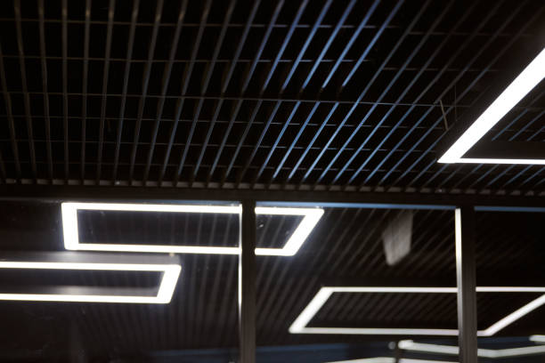 istock Modern office lighting. Thin lamps in office dark ceiling. LED white cold light over workplaces. 1184628400