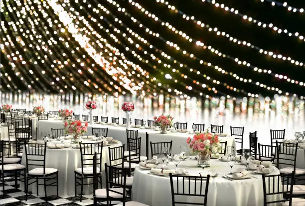 3D Illustration of a wedding reception venue decorated in white with ten seat round tables and a head table on a bokeh background