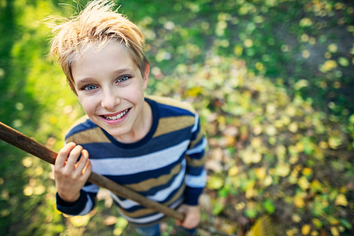 Little boy aged 10 raking autumn leaves in back yard.
Nikon D850