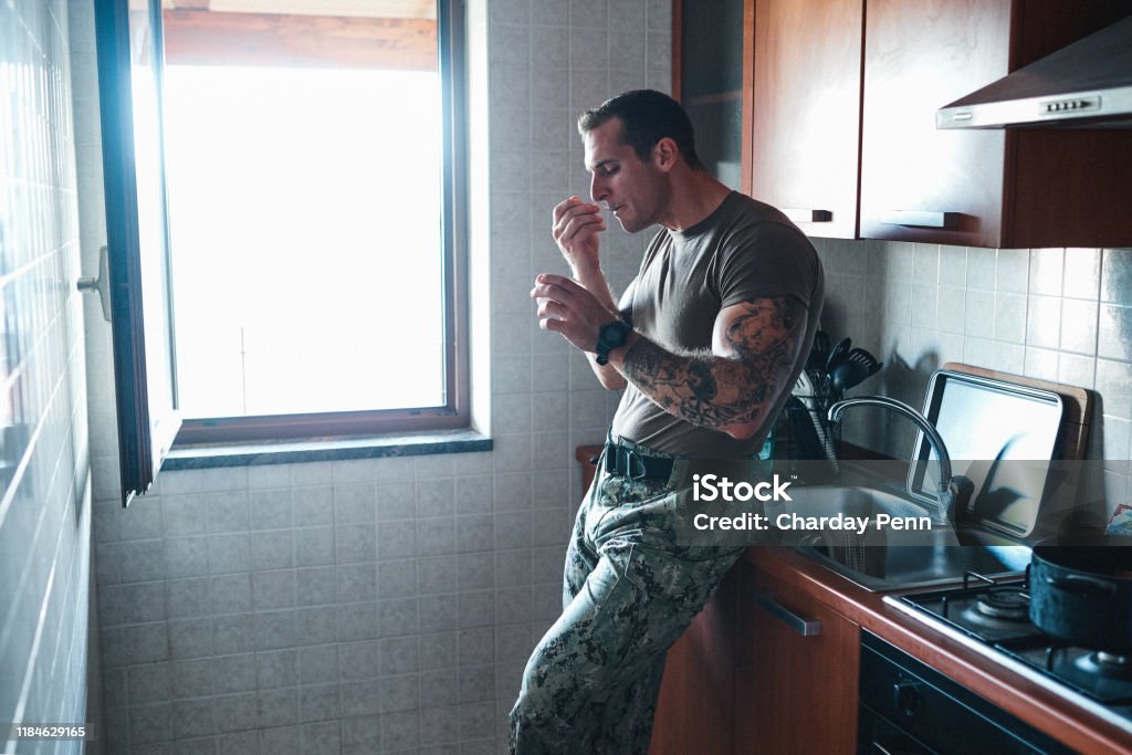 Food is fundamental to staying strong Shot of a young soldier eating a snack in the kitchen Military Stock Photo