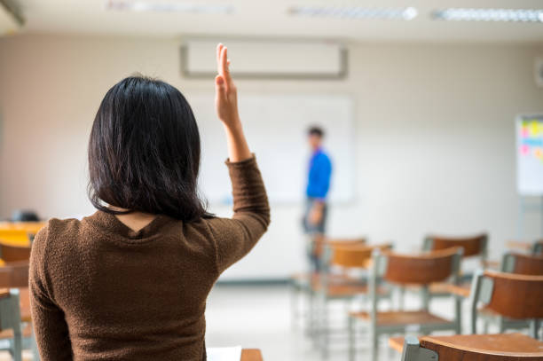 istock Female students raise hands and ask teachers in the university classroom 1184629668