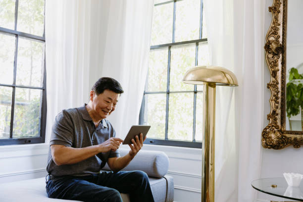 istock Happy man uses digital tablet at home 1184631073