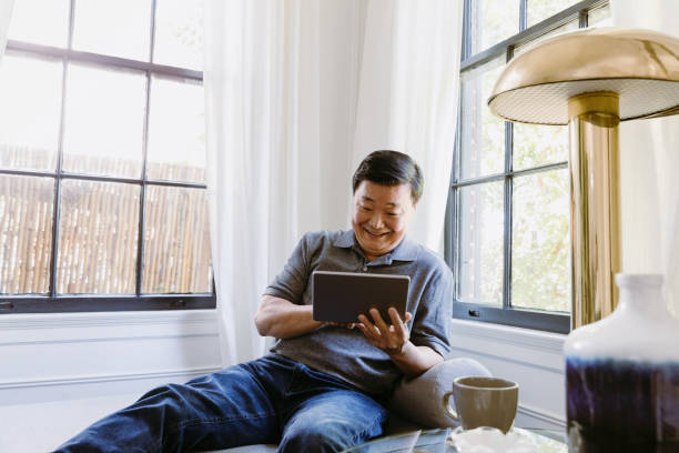 istock Smiling man uses laptop at home 1184631077