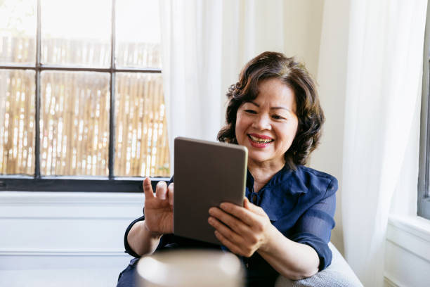 istock Smiling senior woman enjoys using tablet 1184631104