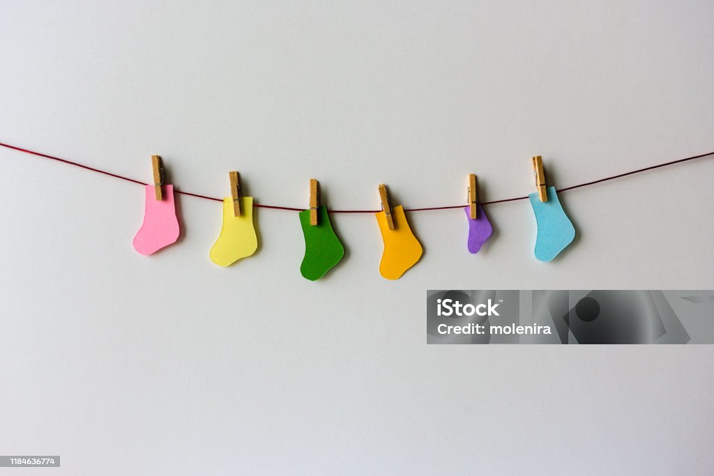 Premature baby day concept. Tiny socks World Prematurity day concept. Normal size and Tiny socks on a red rope Miscarriage Stock Photo